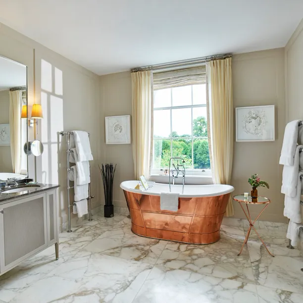 Mansion House Premium Suite bathroom with copper bath by the window at Coworth Park, Ascot