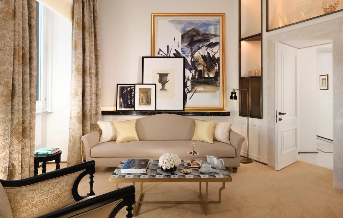 Classic suite living room with beige couch, living table and paintings on the wall