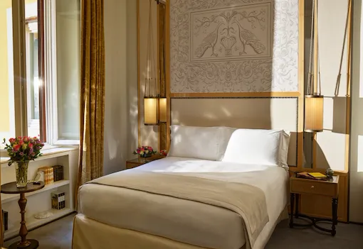 Bedroom of classic room with twin beds, headboard with peacocks illustration and window, at Hotel Eden, Rome