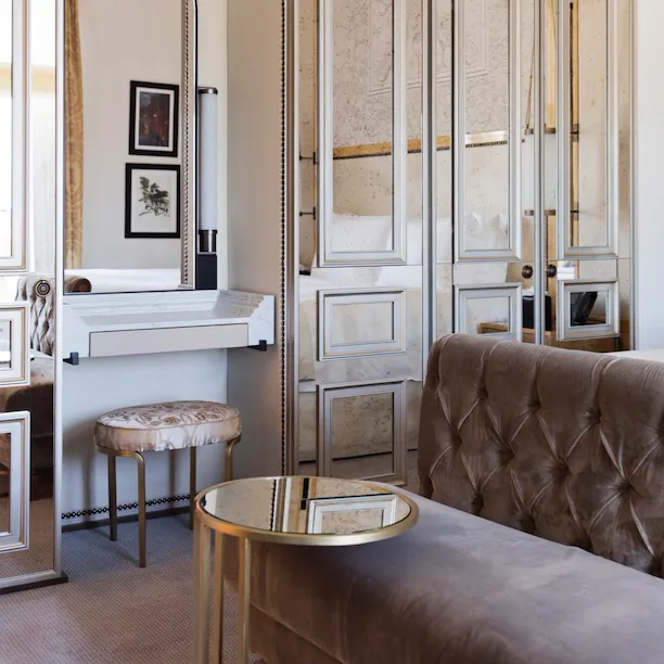 Elegant bedroom with grey couch and vanity station at Hotel Eden, Rome