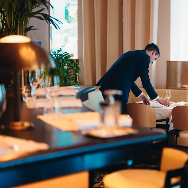 Maitre d'Hotel of Le Relais Plaza drawning up a table with bar counter at the forefront, at Hotel Plaza Athénée, Paris