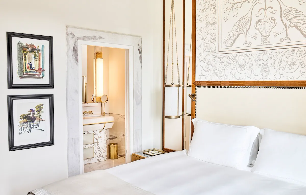 Bedroom of Classic suite with view with paintings on the wall and bathroom in the background at Hotel Eden, Rome