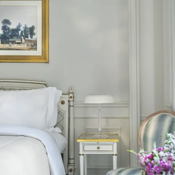 Picture centred on the left side of the bed with the details on the flowers and a chair, at Le Meurice, Paris