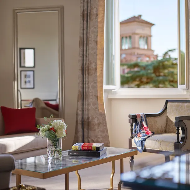 Living Room of Dolce Vita Suite with coffee table, couch, armchairs and windows open to view of Rome at Hotel Eden
