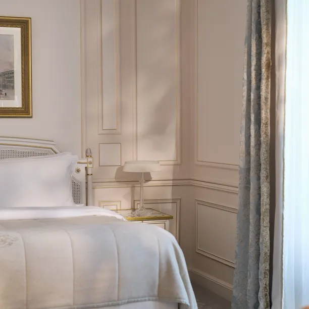 View of the left side of the bed enlighted by the window, at Le Meurice, Paris
