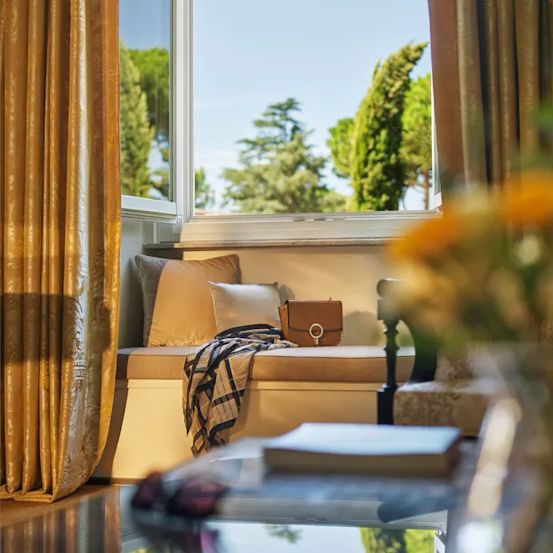 Classic room living room detail with open window and bag on couch at Hotel Eden, Rome