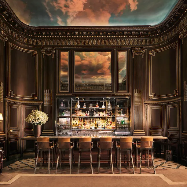 Large view of the counter of the Bar 228 with all the furnitures, the drinks and the painting of clouds on the ceiling reflecting in the miror, at Le Meurice, Paris