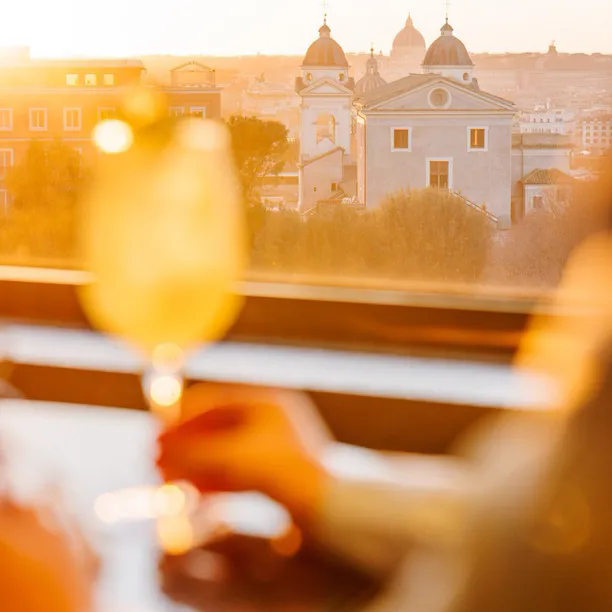 Hand grabbing a drink with Rome sunset view on background at Il Giardino Bar