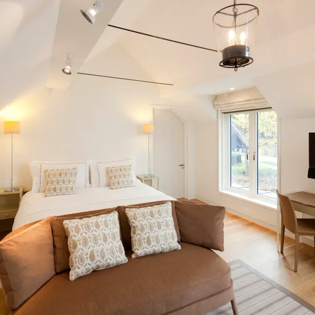 Stable deluxe bedroom interiors with bed, sofa nd television at Coworth Park