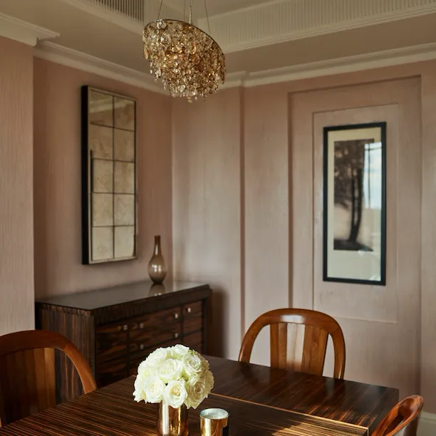 Dining room with white rose bouquet on table and soft pink walls