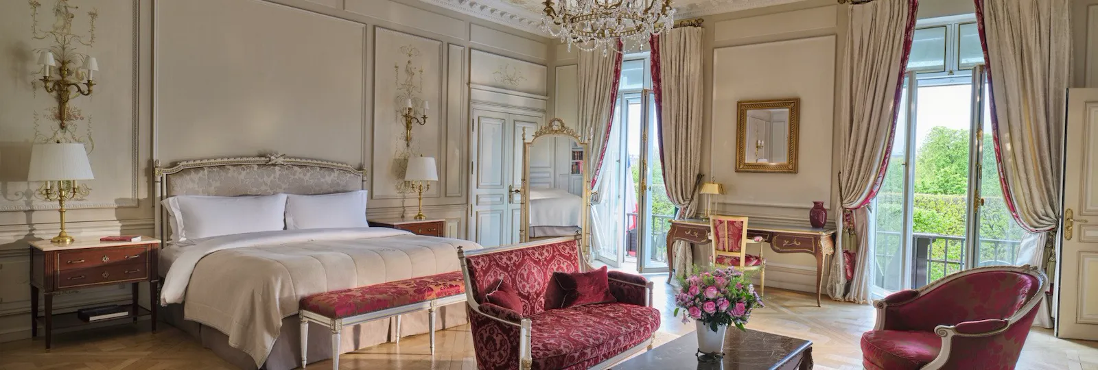 Large view of the Presidential Suite Dali with in first plan the furnitures of a living room like the couch, the rug and the chairs, and in the background the bed and the mirror, at Le Meurice, Paris