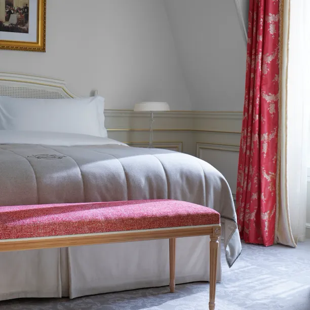 Closeup of bed and bench in front in the bedroom of an executive junior suite at Le Meurice, Paris.