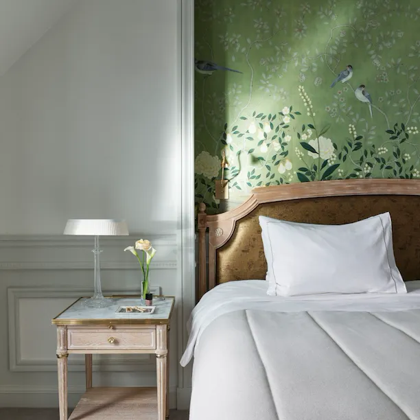 Portrait shot of an executive room with a green hand painted wall, and a wooden side table with a marble top. At Le Meurice, Paris.