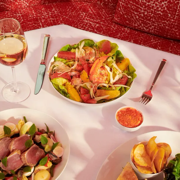 Picture of a lunch at La Terrasse Montaigne with club sandwich, two salads and a glass of wine