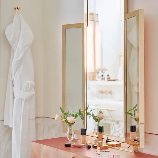 Vanity table with makeup products and bathrobe inside bathroom of Prestige suite at Hotel Eden, Rome