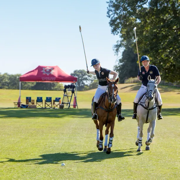 Two people riding horses learning polo at Coworth Park, Ascot
