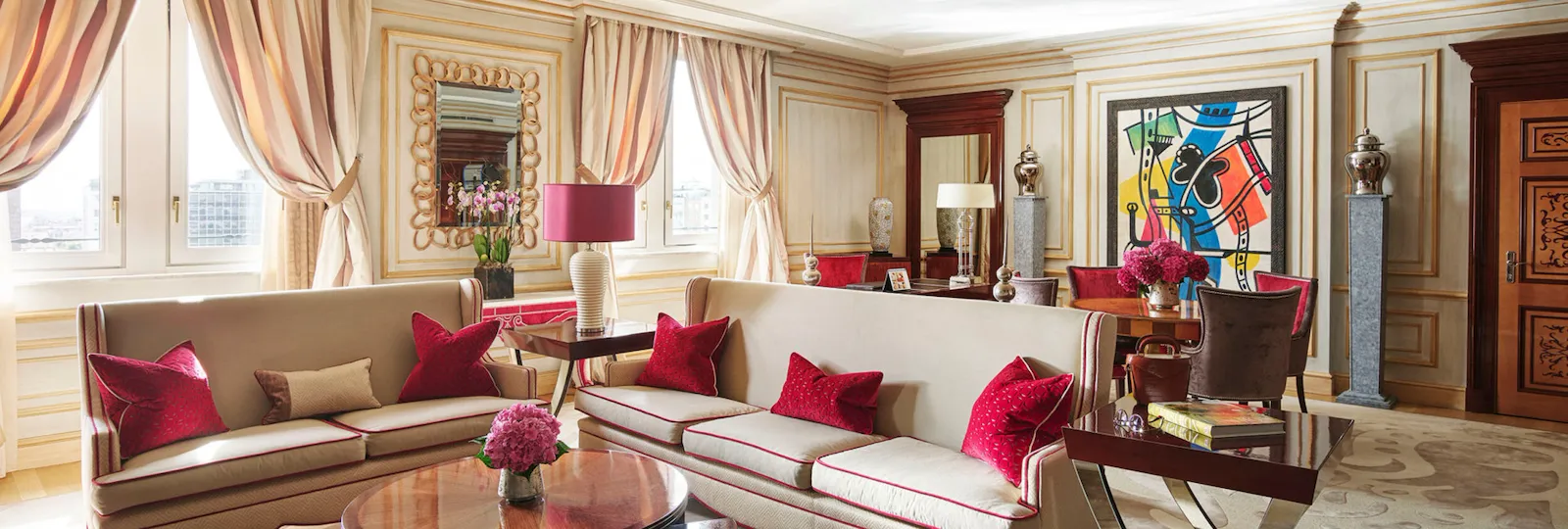 Imperial Executive Suite Living Room furnished with white sofas in the foreground and colourful art pieces in the background