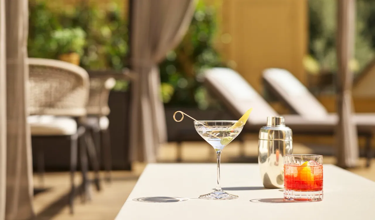 Martini and Negroni cocktails with sunbeds in the background at sunny Aurora Terrace Suite at Hotel Eden, Rome