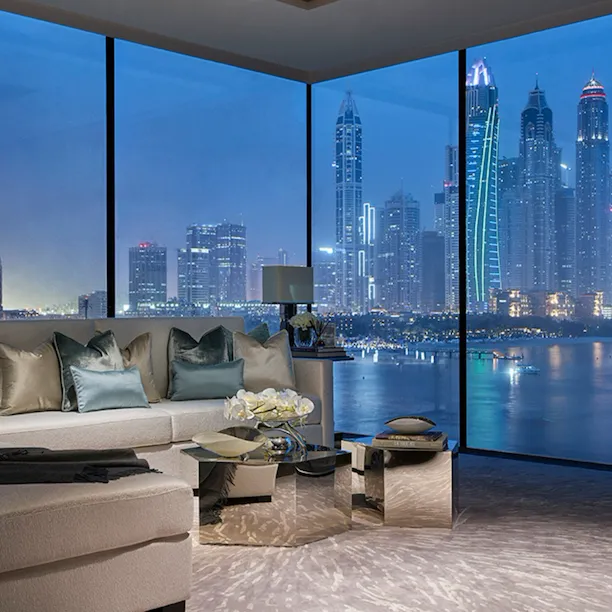 Living area with full height windows showing night time view of Dubai from One at Palm Jumeirah Residences