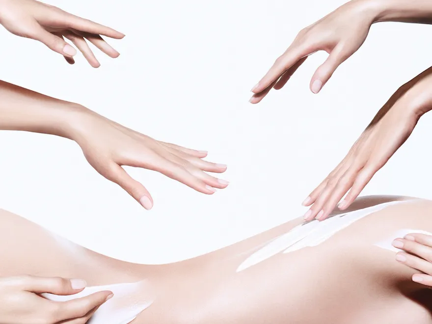 Image of a naked back with some body cream and hands over it