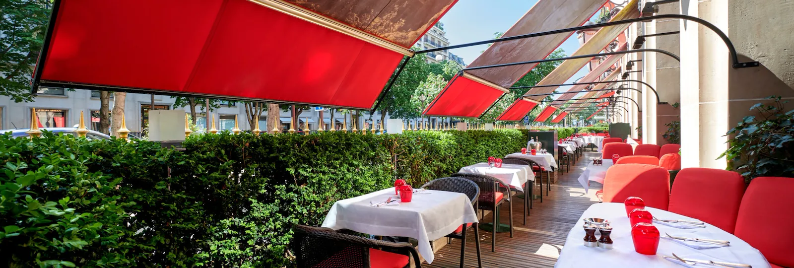 Terrasse Montaigne with drawned up tables, iconic red seats and awnings at Hotel Plaza Athénée, Paris