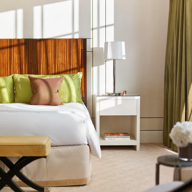 Bright bedroom with white sheets, brown an green interior features in Harlequin Penthouse