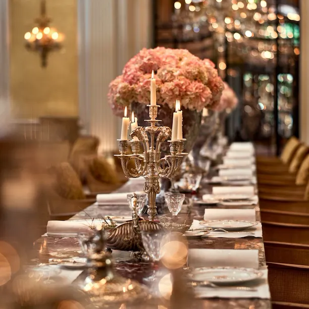 Jean Imbert au Plaza Athénée's central marble table, drawned up with pink flowers and candleholders. At Hotel Plaza Athénée, Paris