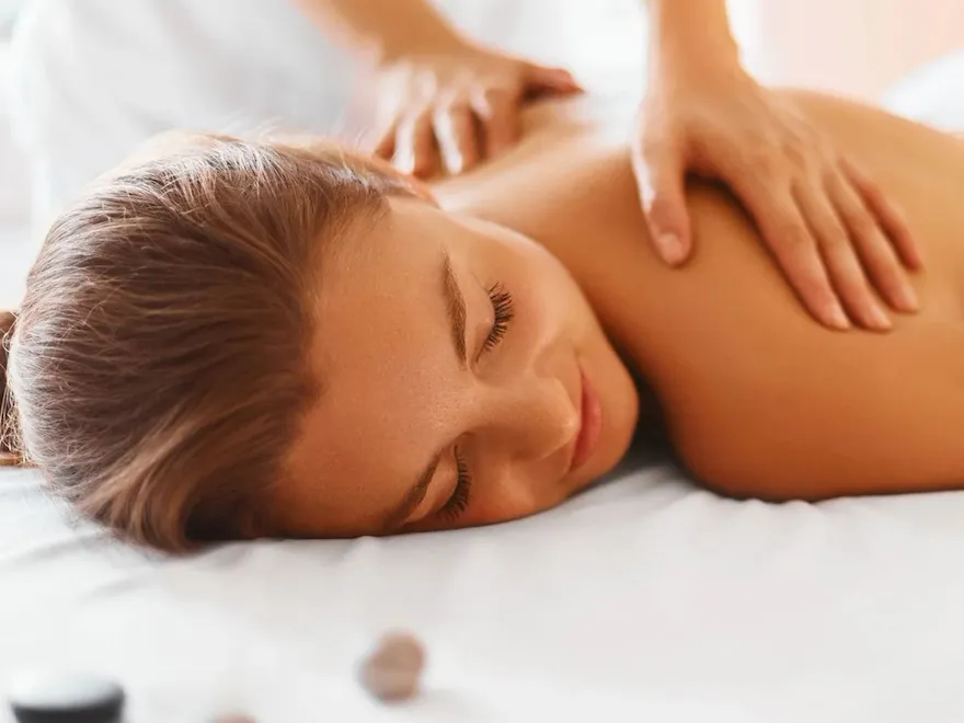 Picture of a woman lying on a message table while someone is massaging her back