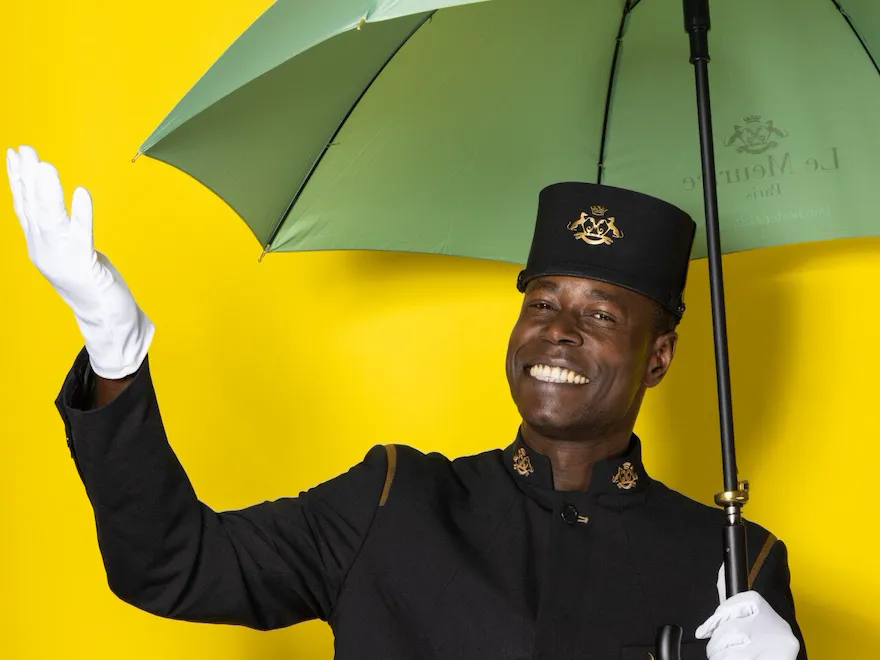 Gadio Mouhadji holding an umbrella against a yellow background
