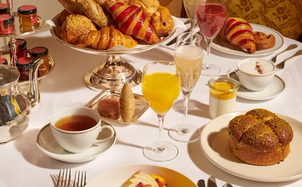 Images of the brunch at the Jean Imbert au Plaza Athénée. There is a bun, some salads, eggs and pastries displayed on the table as well as juices and champagne from a close up angle